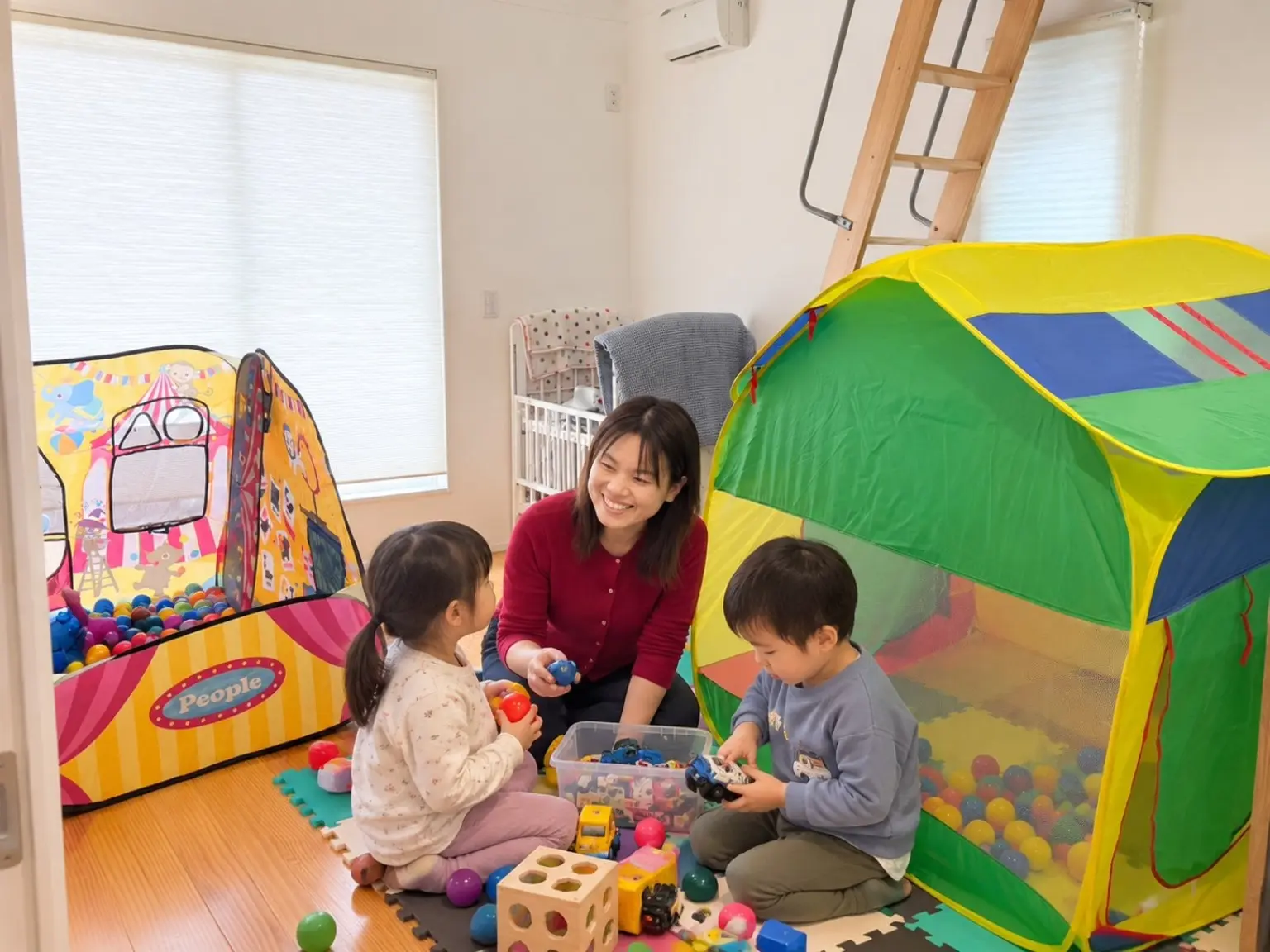 おもちゃやボールプールを備えたキッズスペースで遊ぶ子どもたち